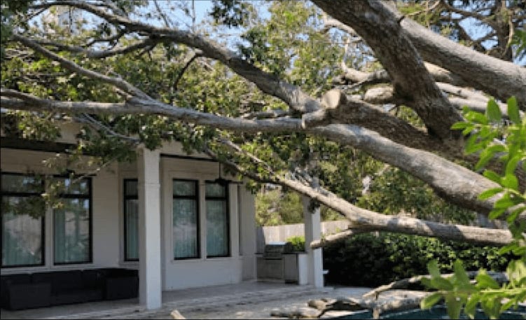 Emergency tree removal crew using a specialized crane to lift a tree off a house in Pace, FL.